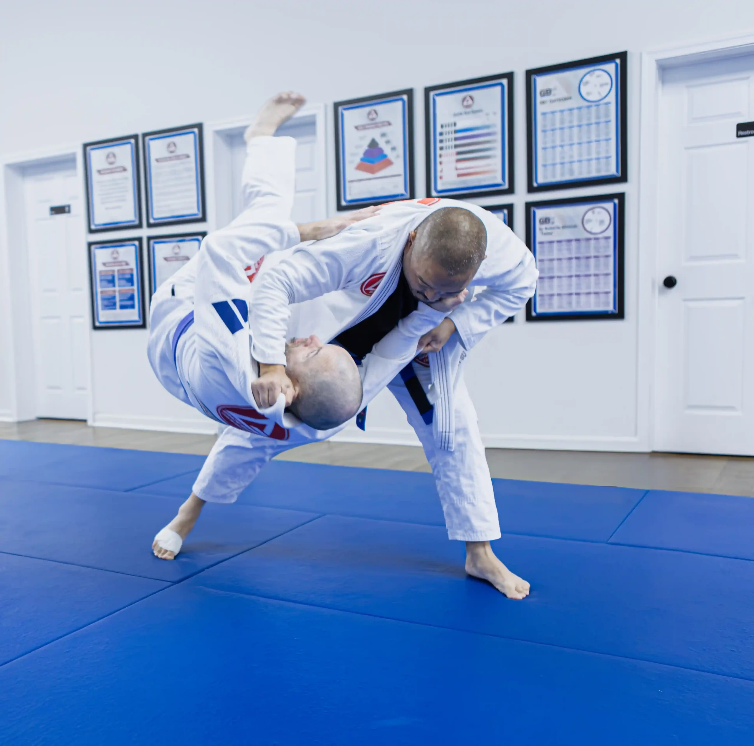 Two adults practicing a Brazilian Jiu-Jitsu ground technique in white uniforms